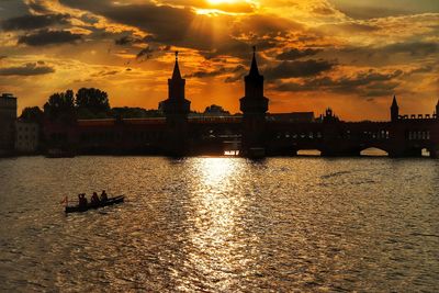 Silhouette of buildings against cloudy sky at sunset