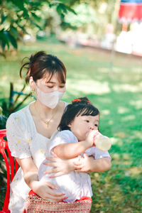 Portrait of young woman drinking water while sitting outdoors