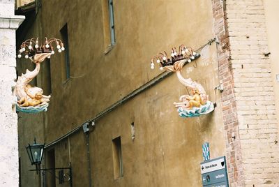 Low angle view of lamps with sculptures mounted on building