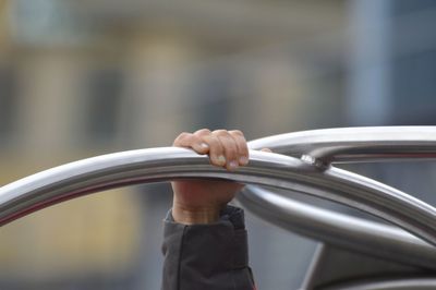 Cropped hand of girl holding metallic railing