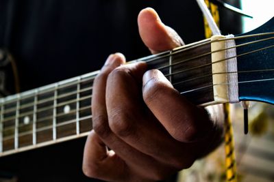 Midsection of man playing guitar 