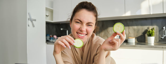 Portrait of young woman holding food at home