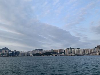 Sea by buildings against sky in city