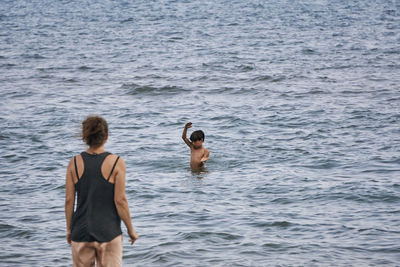 Rear view of shirtless men in sea