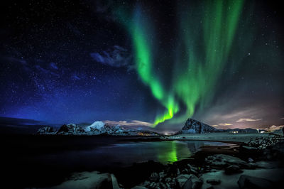 Scenic view of illuminated snowcapped mountains against sky at night