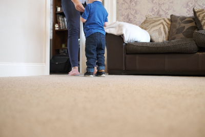 Low section of man standing on sofa at home