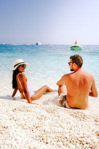 Rear view of men on beach against sky