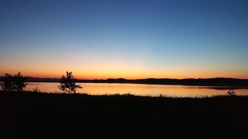 Scenic view of lake against clear sky during sunset