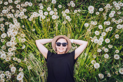 Directly above shot of smiling young woman lying down on dandelions