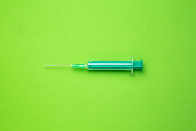 High angle view of syringe on green background