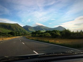 Road by mountains against sky