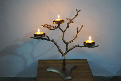 Close-up of illuminated lamp on table against wall