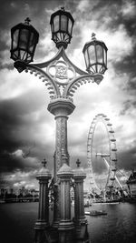 Low angle view of ferris wheel against cloudy sky