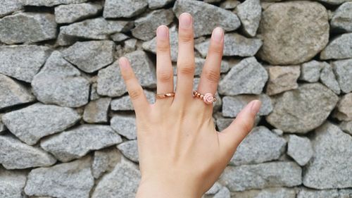 Close-up of female hand against stone wall