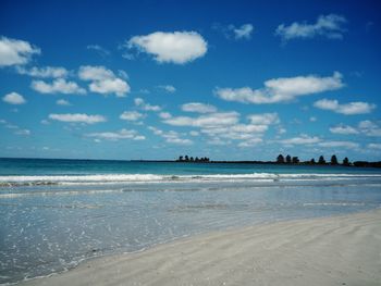 Scenic view of beach against cloudy sky