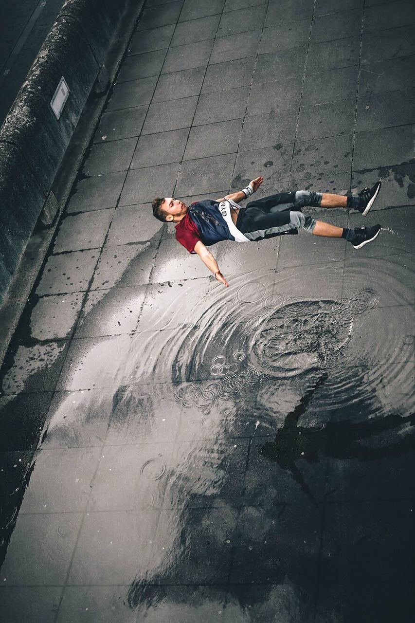 HIGH ANGLE VIEW OF MAN WITH UMBRELLA ON WATER