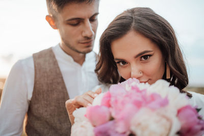 Portrait of a young couple holding pink flower