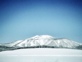 Scenic view of snow covered mountains against blue sky