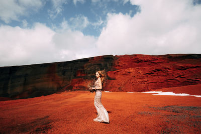 Full length of woman standing on land against sky