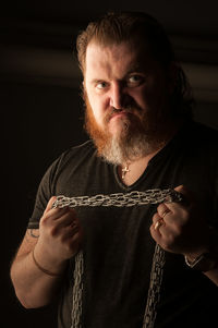 Portrait of mature man standing against black background