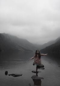 Full length of girl standing on rock in lake 