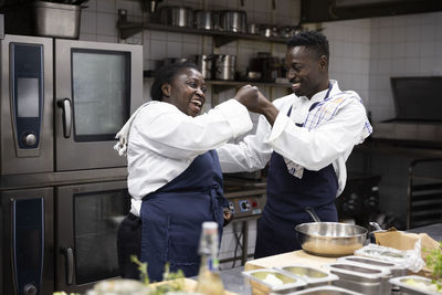 Happy chefs fist bumping while working in restaurant