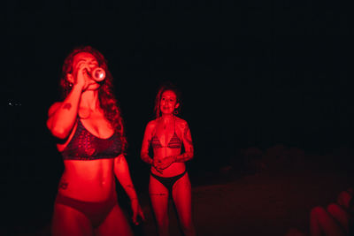 Women illuminated in red under darkness