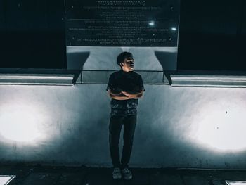 Portrait of young man standing against wall