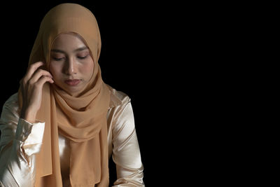 Young woman looking away against black background