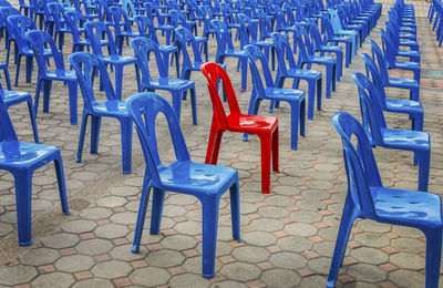 Empty chairs and tables in row against blue sky