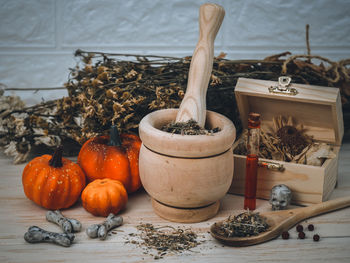 Dried flowers, pumpkins and bones with skulls on a wooden table.