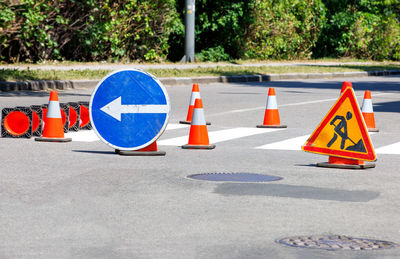 Traffic signs and orange cones line the newly painted crosswalk.