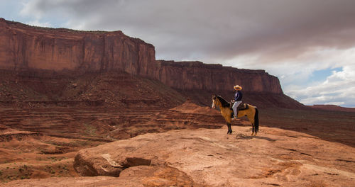 Man sitting on horse at cliff