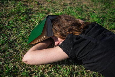 Woman sleeping by book on grass