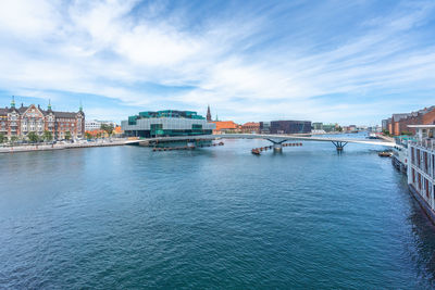 Buildings by river against sky