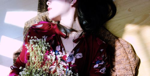 Midsection of woman with flowers lying on hardwood floor