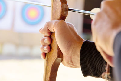 Close-up of man with bow and arrow aiming at target