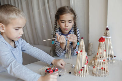 Cute sibling playing with christmas ornaments at home