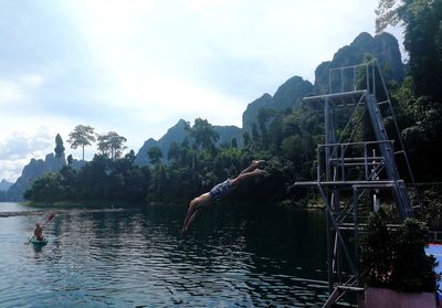 Man by lake against sky