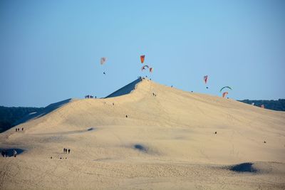 Kites flying over dune of pilat against clear sky