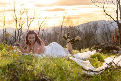 Portrait of young bride laying on field 