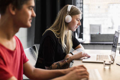 Side view of young businesswoman with colleague working in creative office