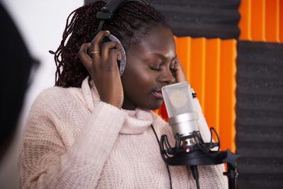 Concentrated singer with eyes closed recording song in studio