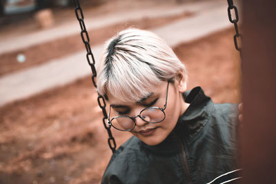 Close-up of woman sitting on swing at playground