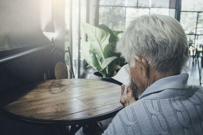 Man sitting on table by window at home