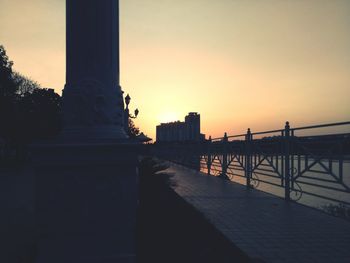 Statue in city against sky at sunset