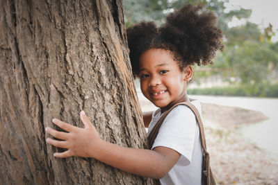 Portrait of smiling girl on tree trunk