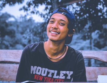 Portrait of smiling young man sitting on bench