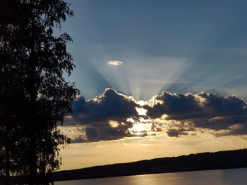 Silhouette trees by lake against sky during sunset