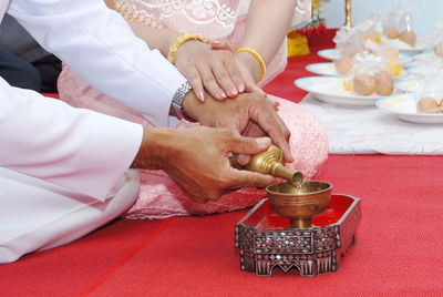 Midsection of man and woman performing rituals during wedding